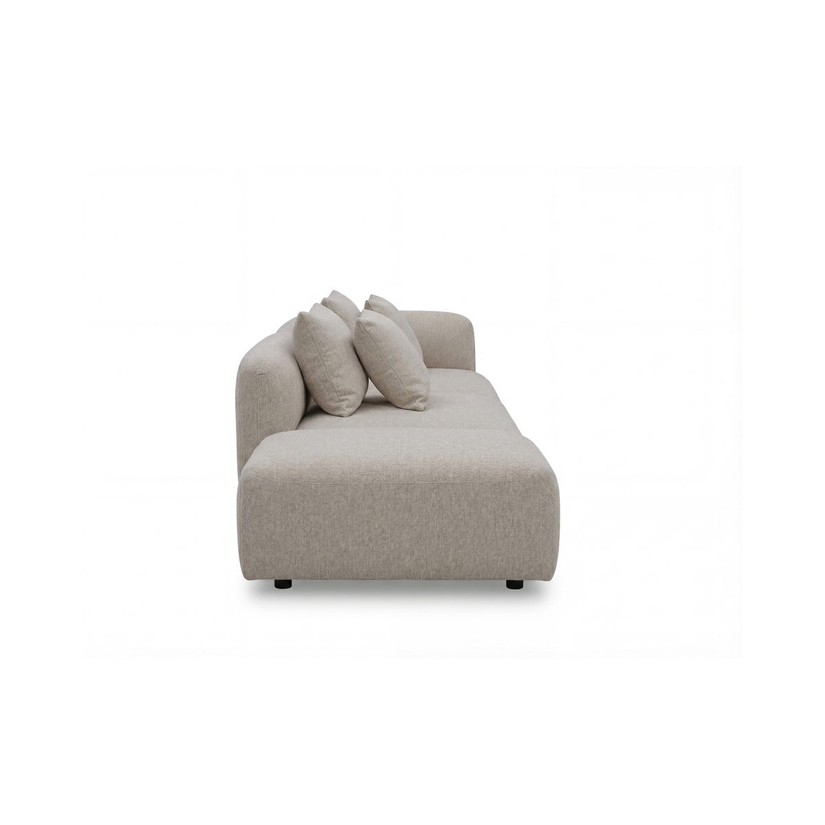 Beige moderne sofa med afrundede former og tre puder, set fra siden mod hvid baggrund.