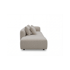 Beige moderne sofa med afrundede former og tre puder, set fra siden mod hvid baggrund.