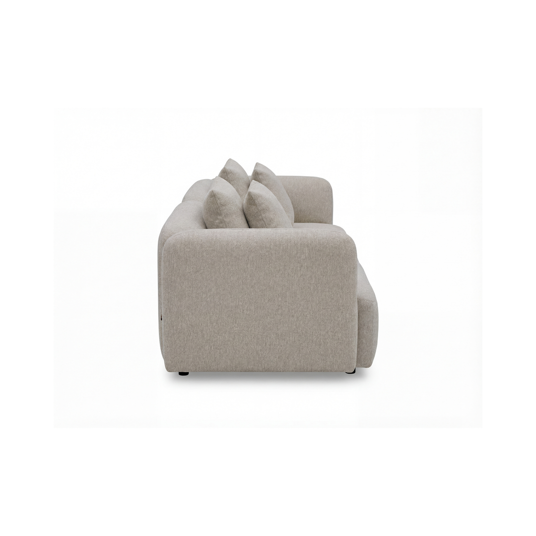 Beige stofsofa med blødt afrundede armlæn og fire ryghynder, fotograferet fra siden mod hvid baggrund.