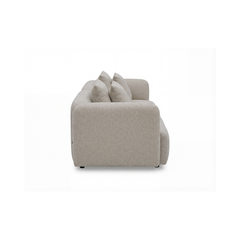 Beige stofsofa med blødt afrundede armlæn og fire ryghynder, fotograferet fra siden mod hvid baggrund.