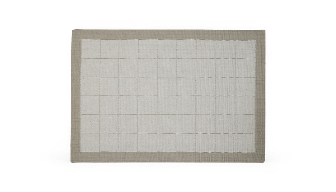 Lysegråt tæppe med diskret ternet mønster og beige/taupe kant hele vejen rundt.
