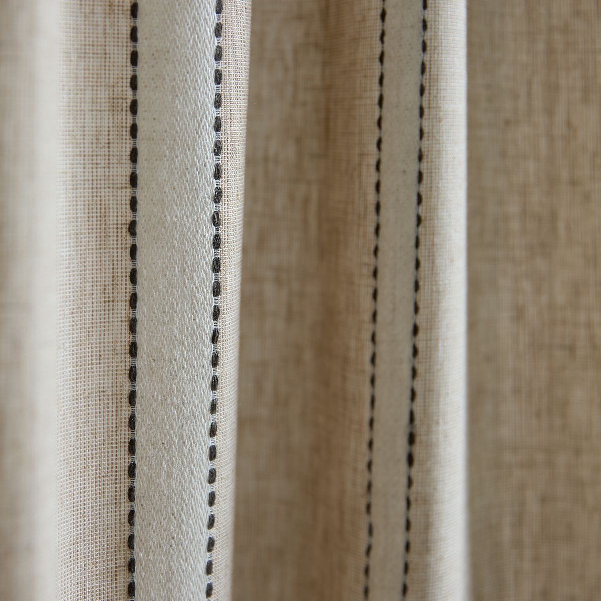 Nærbillede af beige linnedgardin med lodrette sorte syede striber.