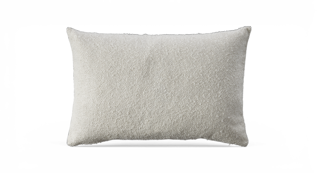 Rektangulær offwhite pude med tekstureret stof mod sort baggrund.