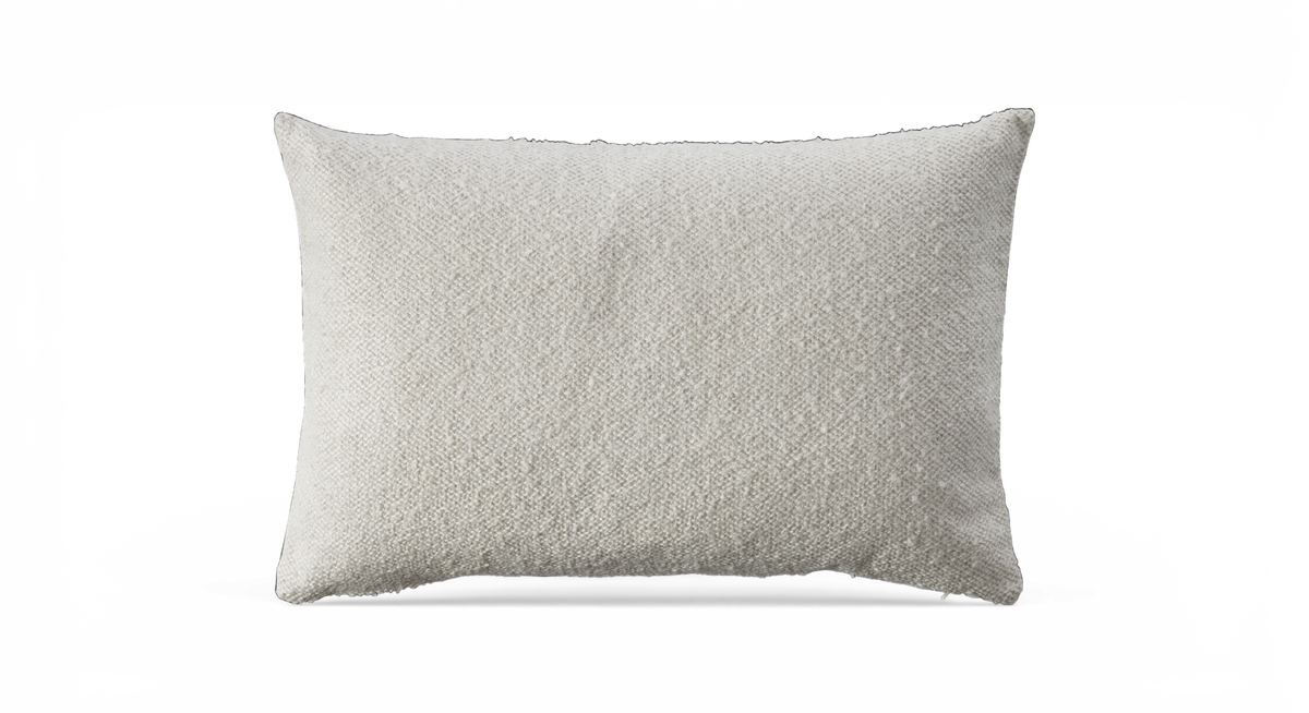 Rektangulær offwhite pude med tekstureret stof mod sort baggrund.