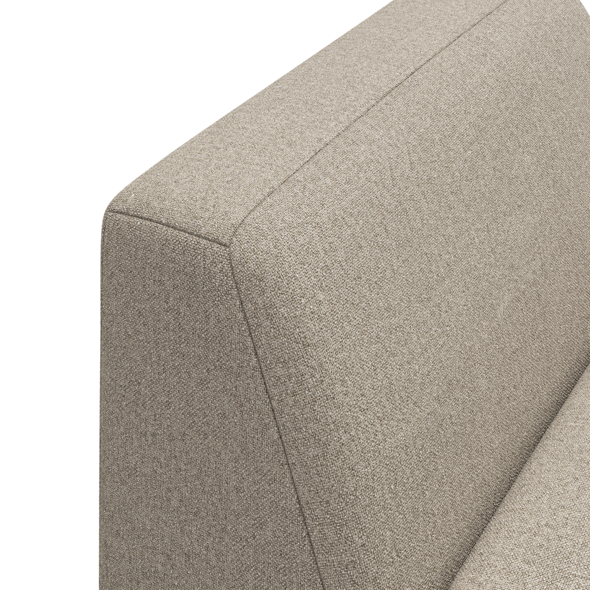 Nærbillede af beige stofbetrukket sofa – hjørnet mellem ryglæn og armlæn.