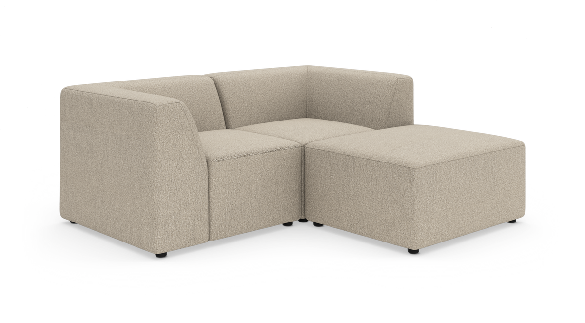 Beige modulsofa med hjørnemodul og stor ottoman på hvid baggrund.