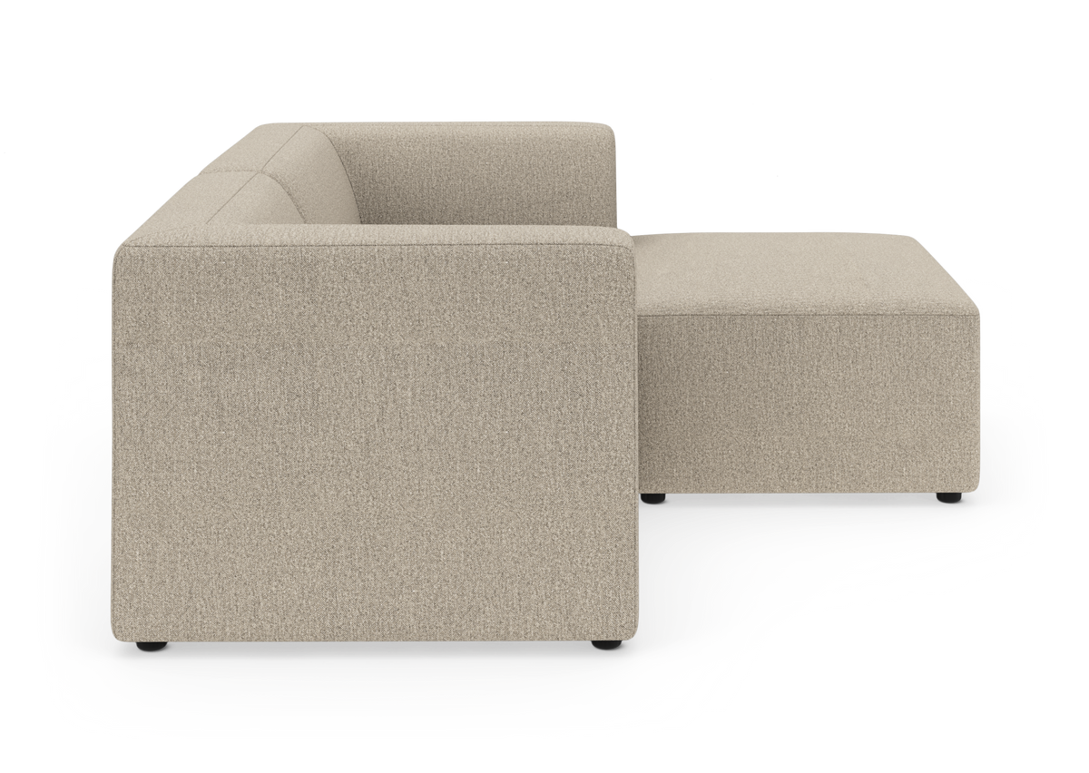 Beige modulsofa med chaiselong, set fra siden på hvid baggrund.