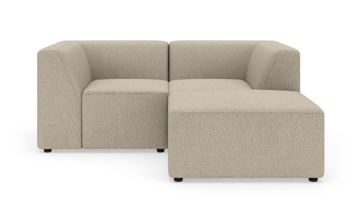 Modulær hjørnesofa i beige stof, L-formet med lave sorte ben på hvid baggrund.