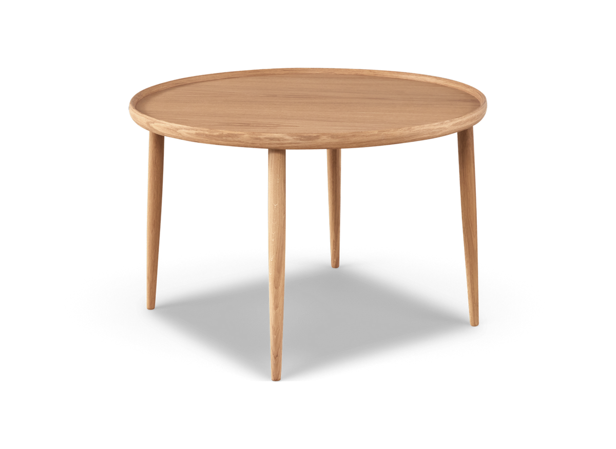 Rundt sofabord i lys eg med hævet kant og fire slanke, tilspidsede ben, frilagt mod hvid baggrund.