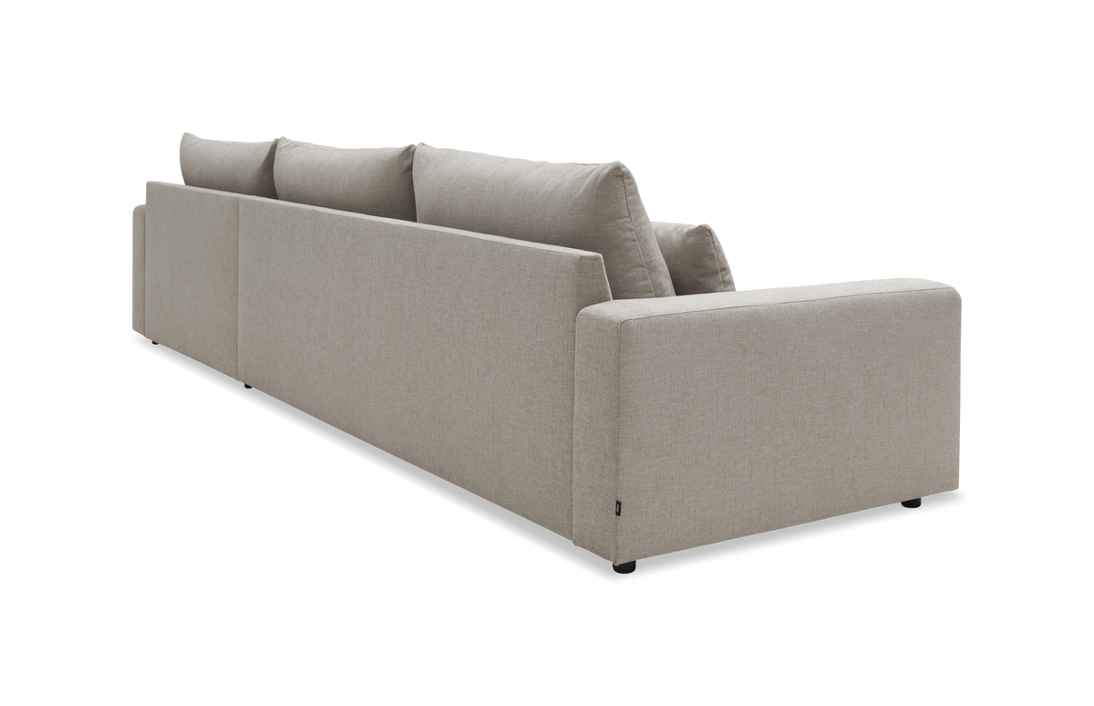 Beige stofsofa set bagfra i skrå studiovinkel med tre løse ryghynder og rene, boxede linjer.