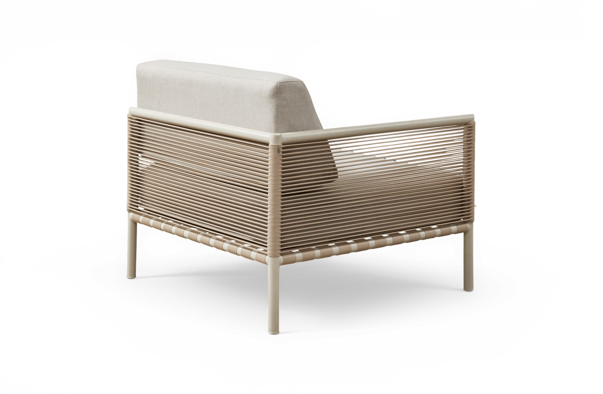 Lys beige loungestol med snoreomviklet ram og lyse hynder, set skråt bagfra.