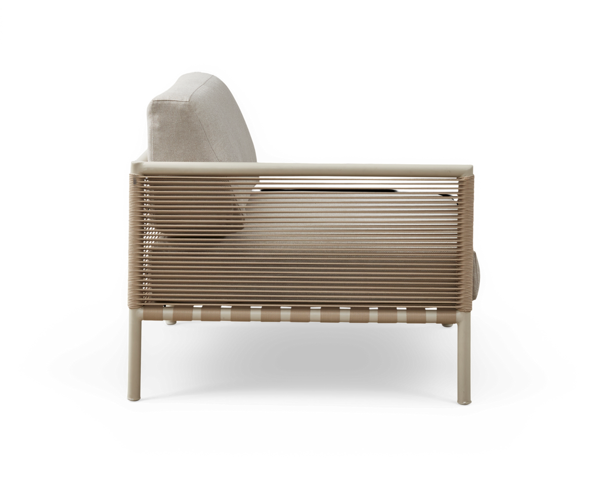 Beige loungestol i sideview med snøret ramme og polstrede puder på slankt metalstel.