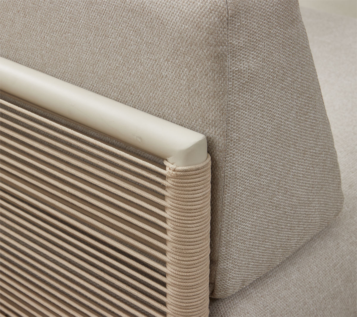 Nærbillede af beige sofaryg med tekstureret pude og armlæn med snoret detalje.