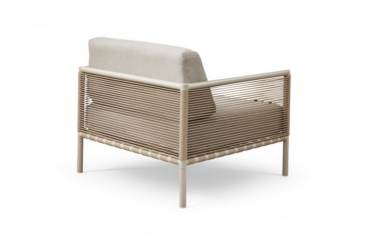 Beige loungestol med snoredetaljer og hynder, set skråt bagfra på frilagt baggrund.