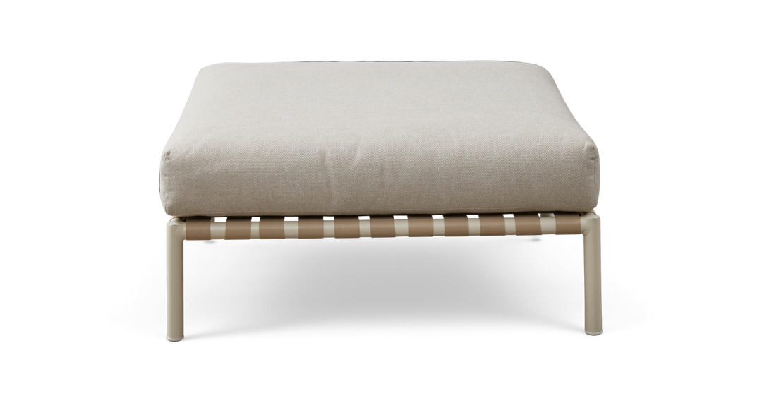 Beige puf/ottoman med tyk pude på lys metalramme med vævede remme, set forfra.