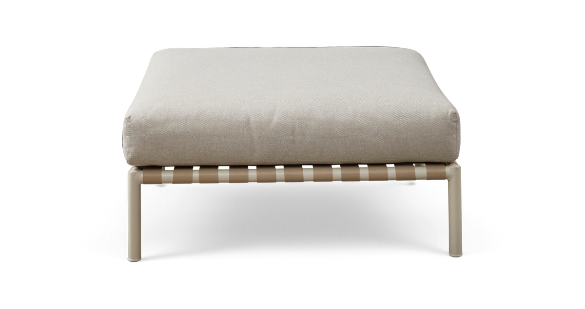 Beige puf/ottoman med tyk pude på lys metalramme med vævede remme, set forfra.
