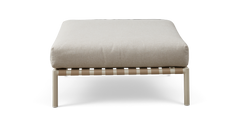 Beige puf/ottoman med tyk pude på lys metalramme med vævede remme, set forfra.