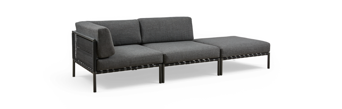 Modulær 3-personers sofa med chaiselong, grå polstring og sort metal-/reb-ramme, fritlagt på sort baggrund.