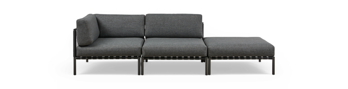 Modulær mørkegrå 3-personers sofa med chaiselong til højre, set forfra på fritlagt hvid baggrund.