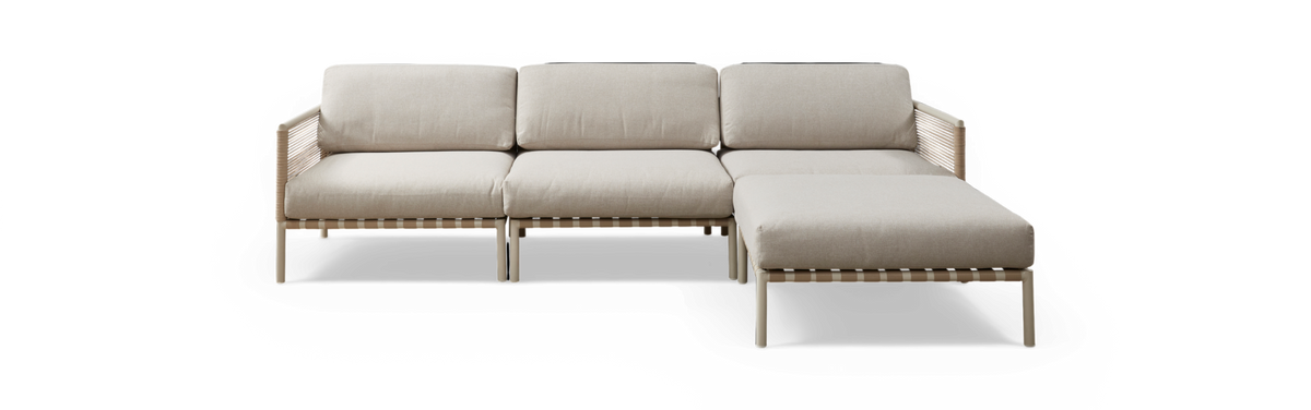 Beige modulsofa med chaiselong til højre, flettede sider og metalben, frilagt på sort baggrund.