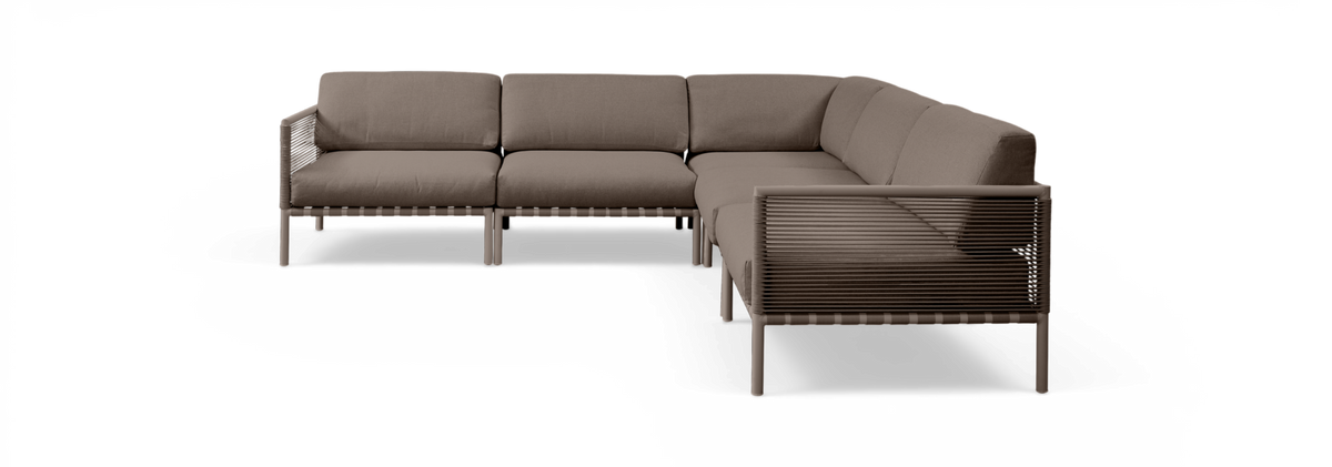 Brun L-formet modulsofa med snoromviklede sider og tykke hynder, frilagt på sort baggrund.