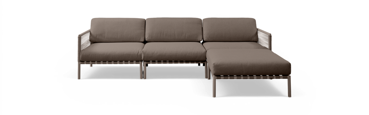 Brun modulsofa med chaiselong til højre, frilagt mod sort baggrund.