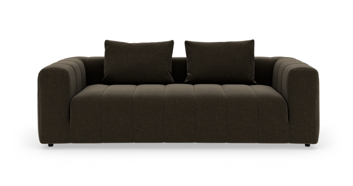 Mørkebrun moderne 3‑personers sofa med to ryghynder, brede armlæn og kanalstukket sæde, frilagt mod hvid baggrund.
