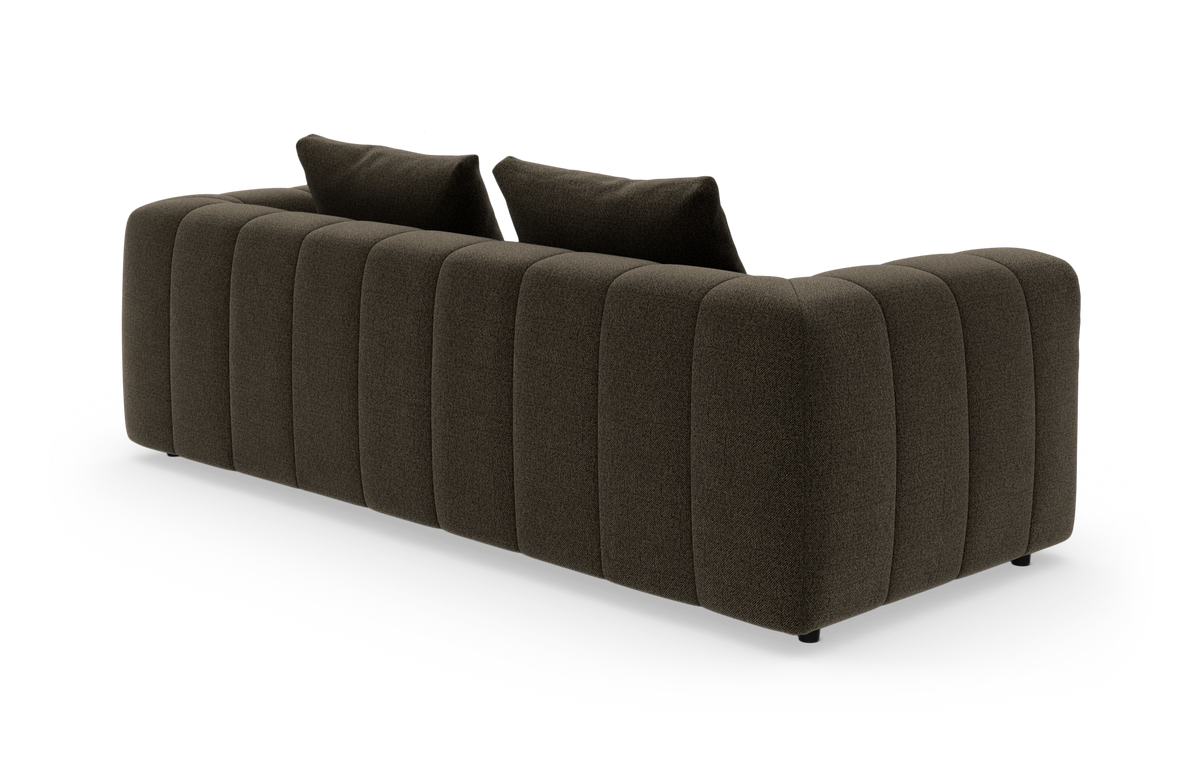Mørkebrun, rundet sofa med lodrette polstrede paneler og to rygpuder, set skråt bagfra på hvid baggrund.