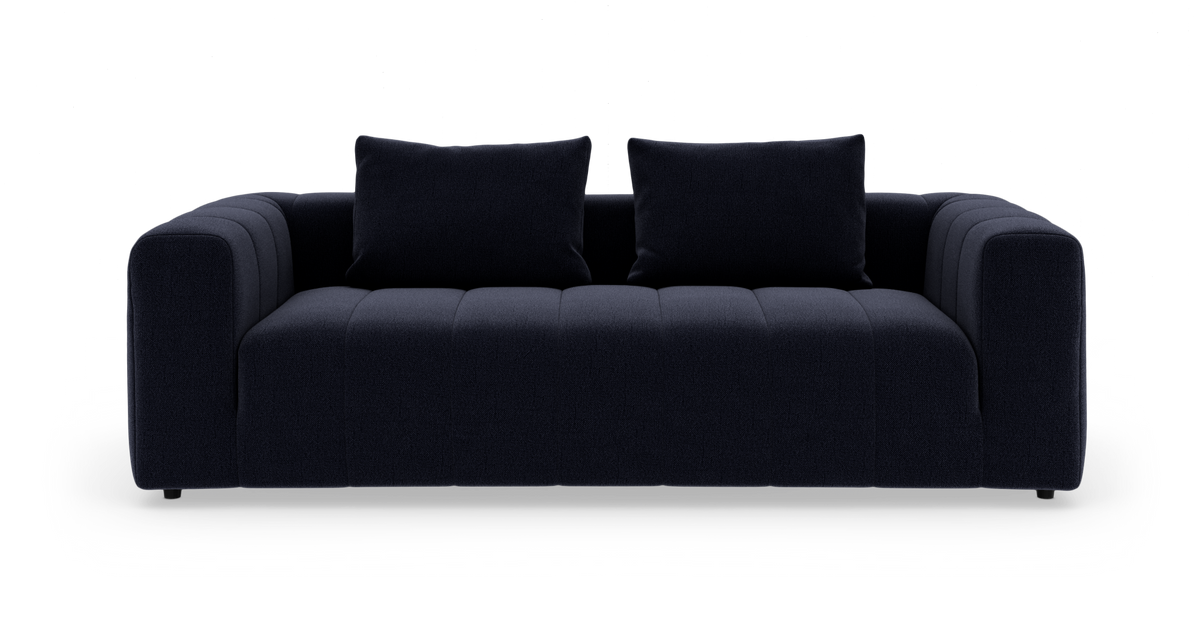 Mørkeblå, moderne 3-personers sofa med to puder, fotograferet lige forfra på hvid studiobaggrund.