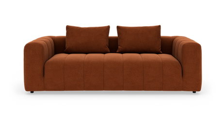Rustfarvet sofa med to puder, brede afrundede armlæn og kanalpolstret sæde på hvid baggrund.