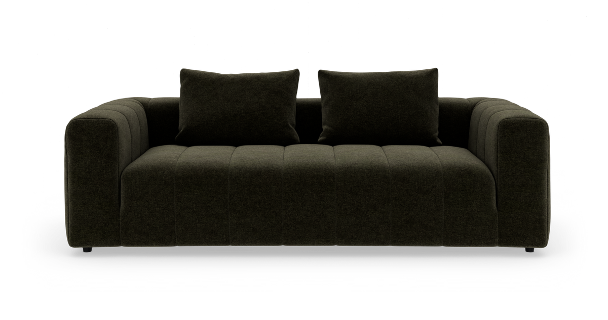Mørkegrøn sofa med to rygpuder, fotograferet lige forfra mod hvid baggrund.