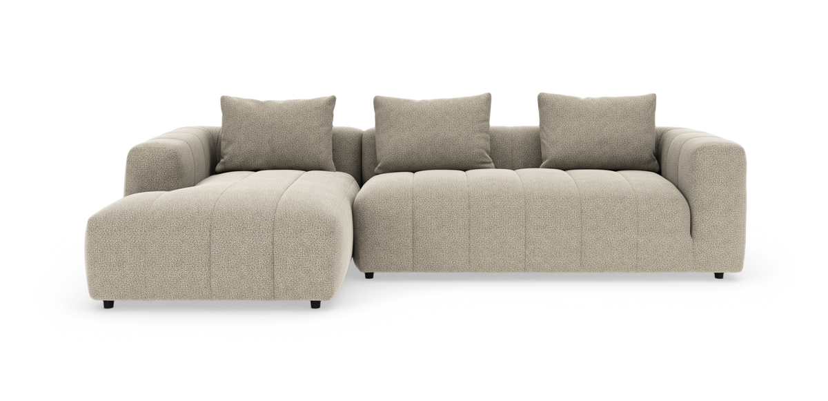 Beige modulsofa med chaiselong til venstre, tre rygpuder og blødt afrundede armlæn, frilagt på hvid baggrund.