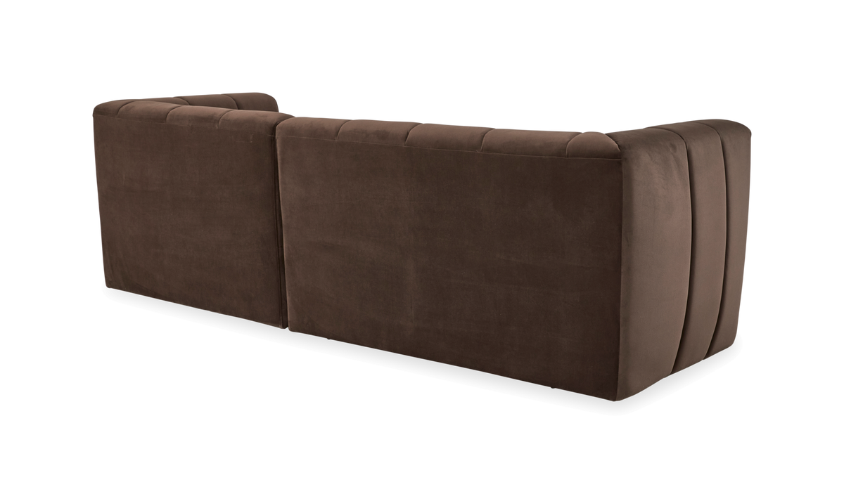 Brun velour modulsofa set bagfra med afrundede hjørner og diskrete lodrette syninger, frilagt på hvid baggrund.