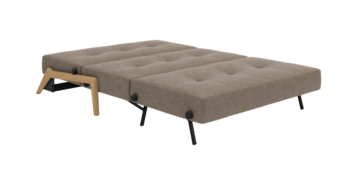 Sovesofa i udslået sengestilling med beige, tuftet madras, sorte metalben og træben.