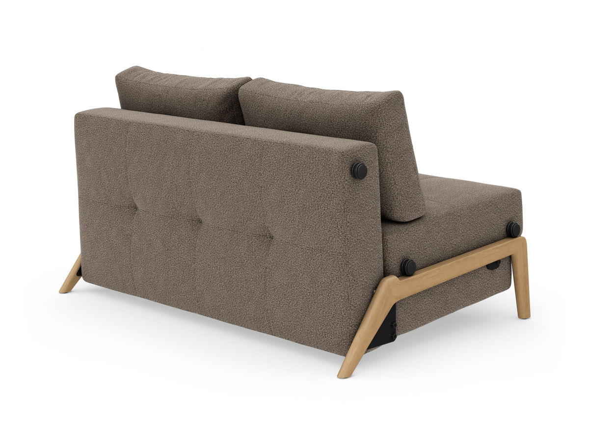 Brun stofsofa med træben set skråt bagfra på hvid baggrund.