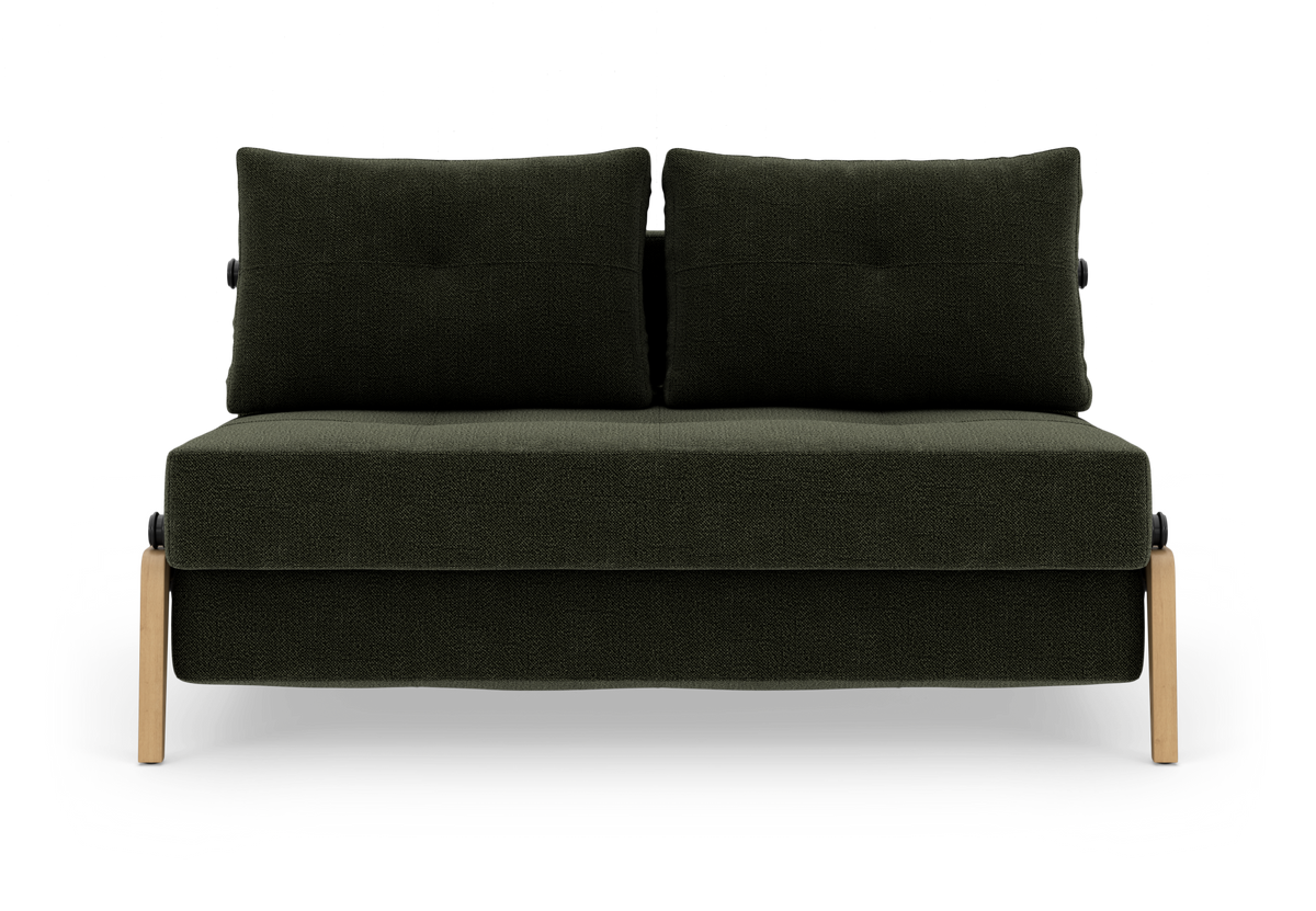 Mørkegrøn to-sæders sofa med to ryghynder og lyse træben, frilagt på hvid baggrund.
