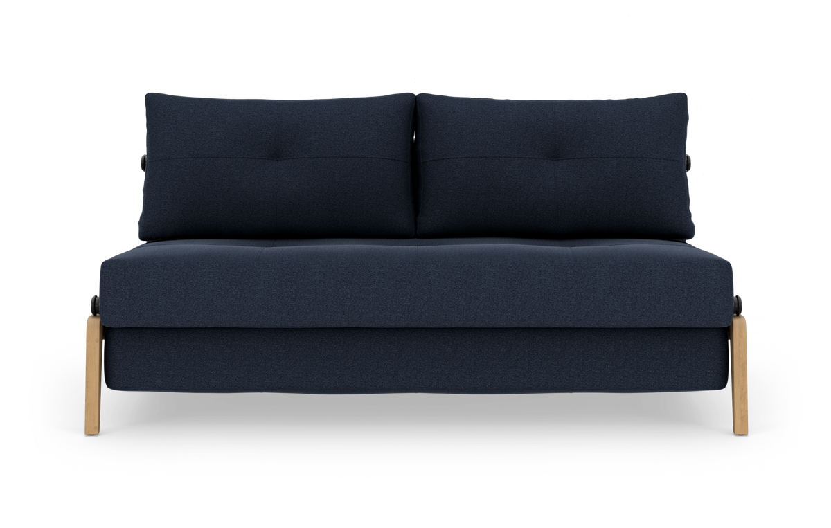 Mørkeblå tosædet sofa med to ryghynder og lyse træben, fotograferet lige forfra mod hvid baggrund.