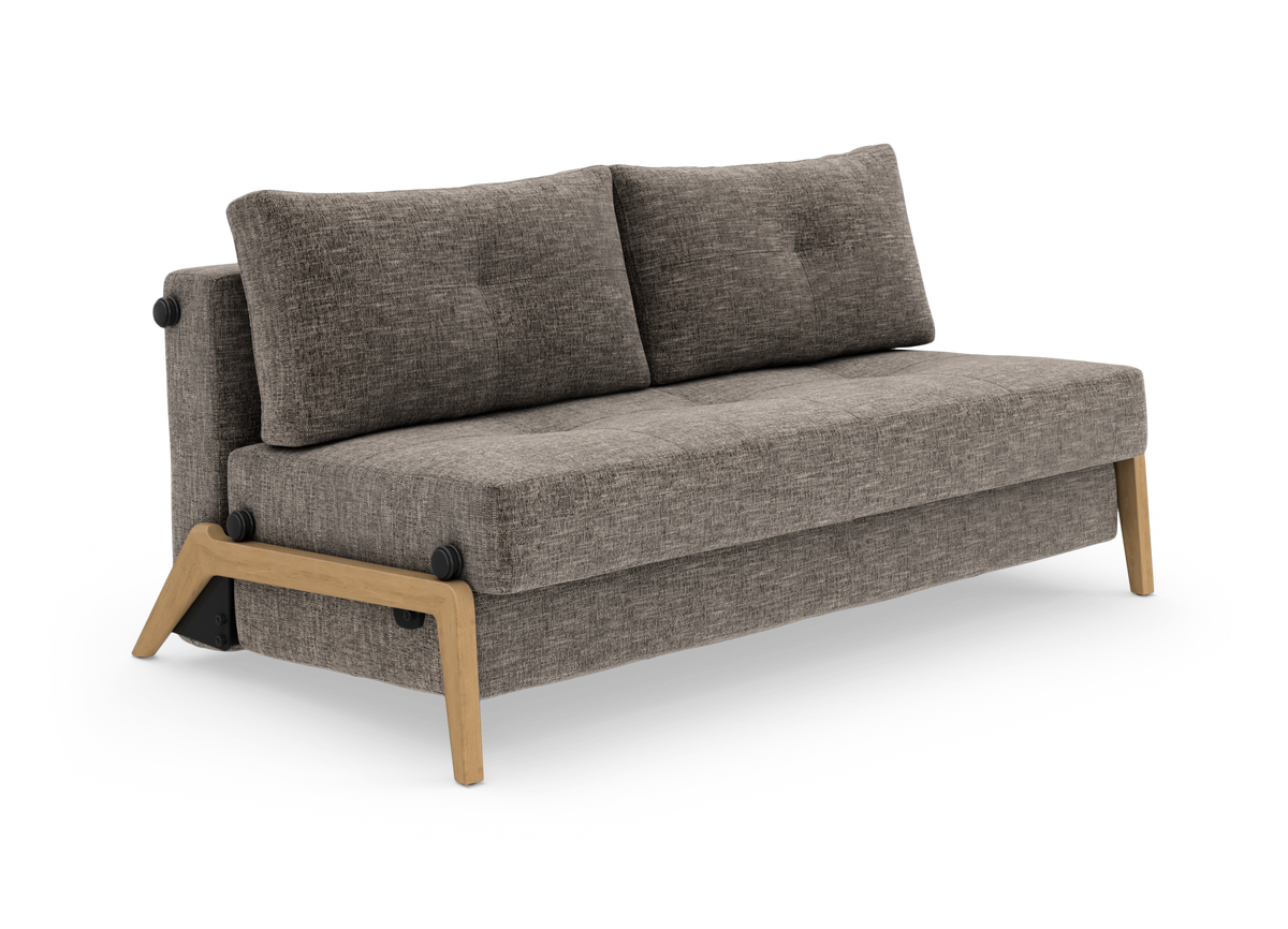 Grå sofa med træben og to ryghynder, frilagt på hvid baggrund i vinklet visning.