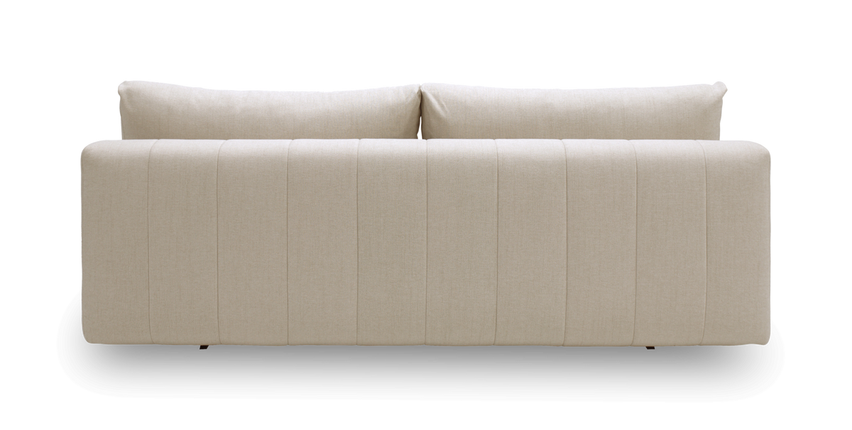 Beige stofsofa set bagfra med lodrette paneler og to ryghynder.