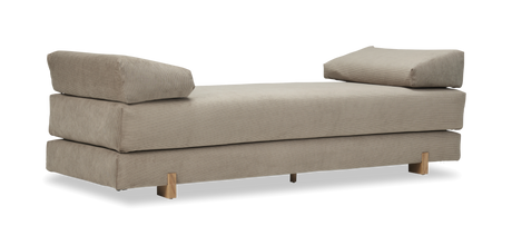 Beige daybed i cordfløjl med to skrå puder og træben, frilagt.
