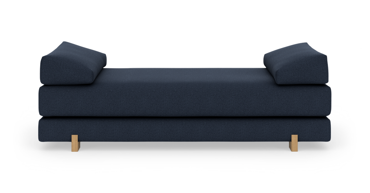 Mørkeblå moderne daybed med to skråtstillede armpuder og lyse træben, frilagt på hvid baggrund.