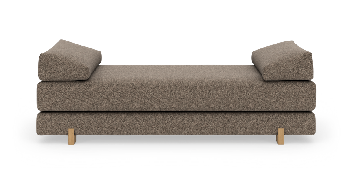 Brun/beige daybed i stof med to kileformede sidepuder og lave træben, frilagt front.