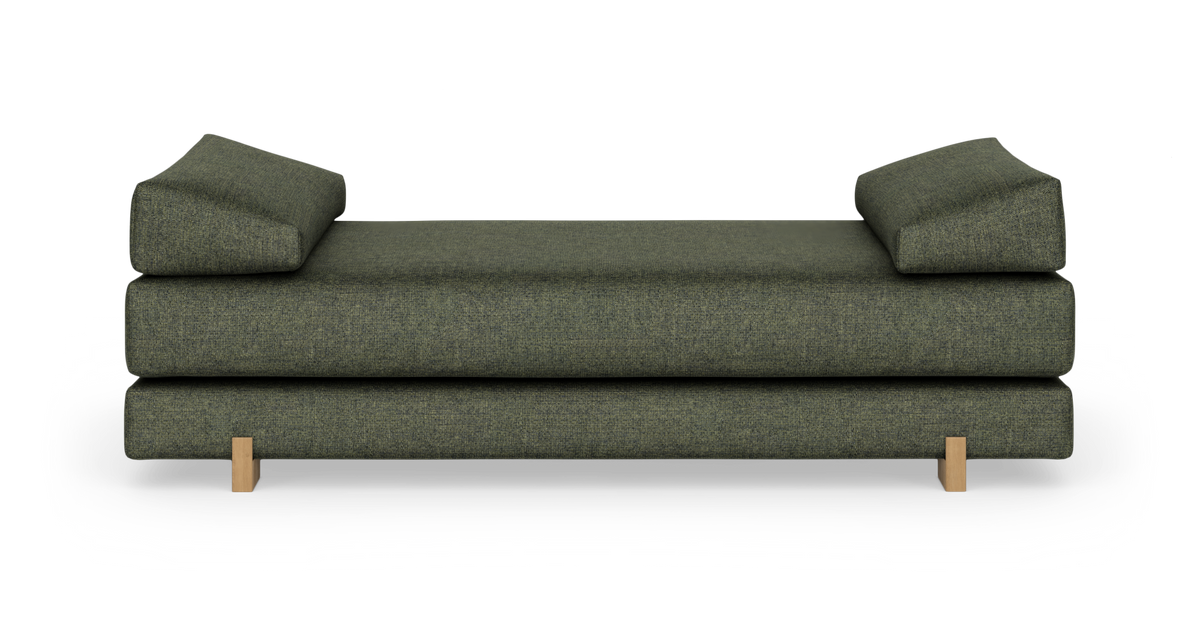Grøn daybed/sofa med to kileformede rygpuder og træben, frilagt på hvid baggrund.