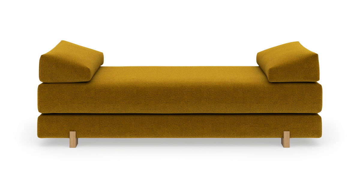 Sennepsgul daybed/sofa med lave armpuder, frilagt på hvid baggrund.