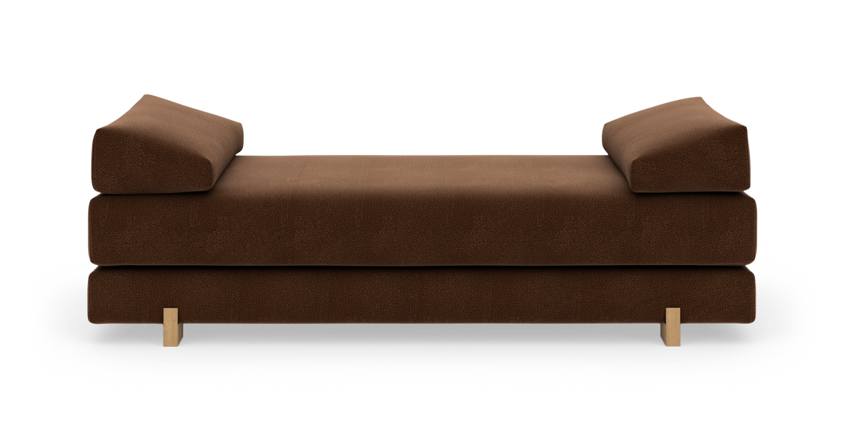 Brun modulsofa/daybed med skrå armlæn og lyse træben, frilagt på hvid baggrund.