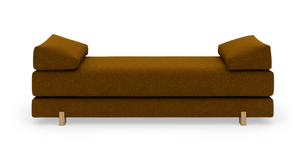 Daybed i rustbrun bouclé med skrå armpuder og træben, frilagt på hvid baggrund.