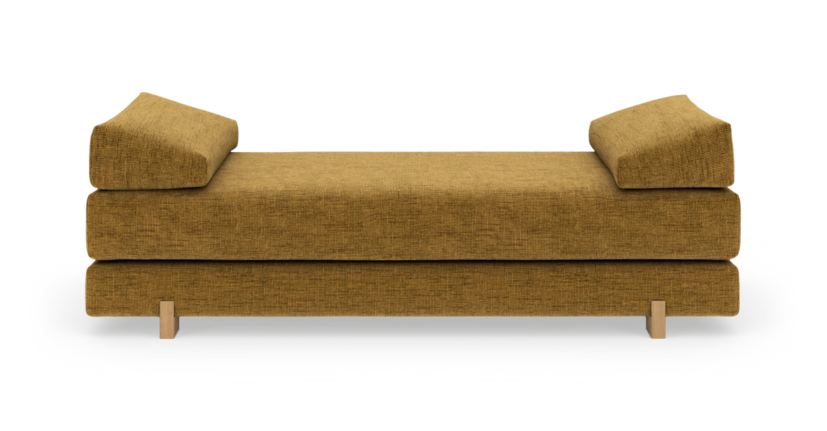Sennepsgul daybed med to kileformede ryghynder og lyse træben, frilagt på hvid baggrund.