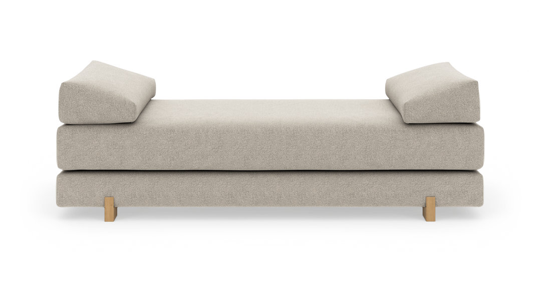 Beige daybed med to vinklede armlænspuder og lyse træben, frilagt på hvid baggrund.