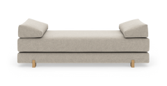 Beige daybed med to vinklede armlænspuder og lyse træben, frilagt på hvid baggrund.