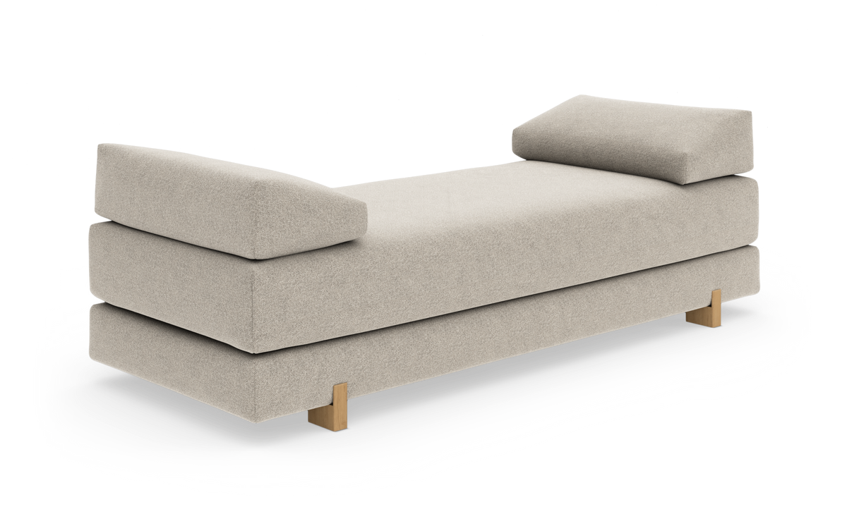 Beige daybed med bløde bolster i begge ender og træben, frilagt på hvid baggrund.